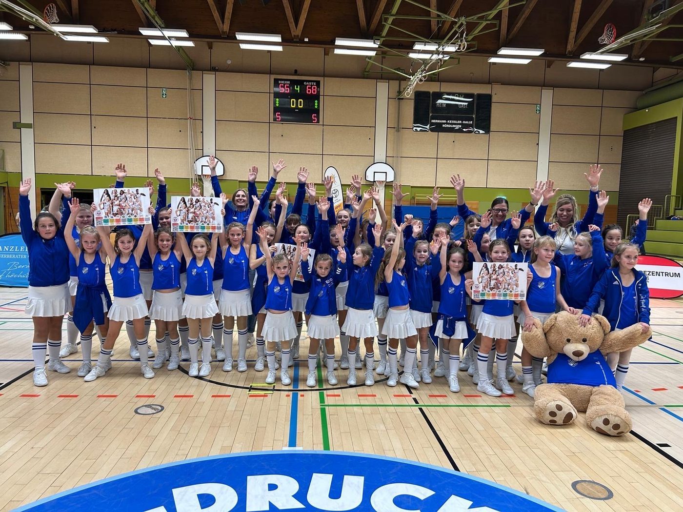 Große Gruppe der Dancers in blau-weißen Kostümen bei einem Auftritt in der Sporthalle