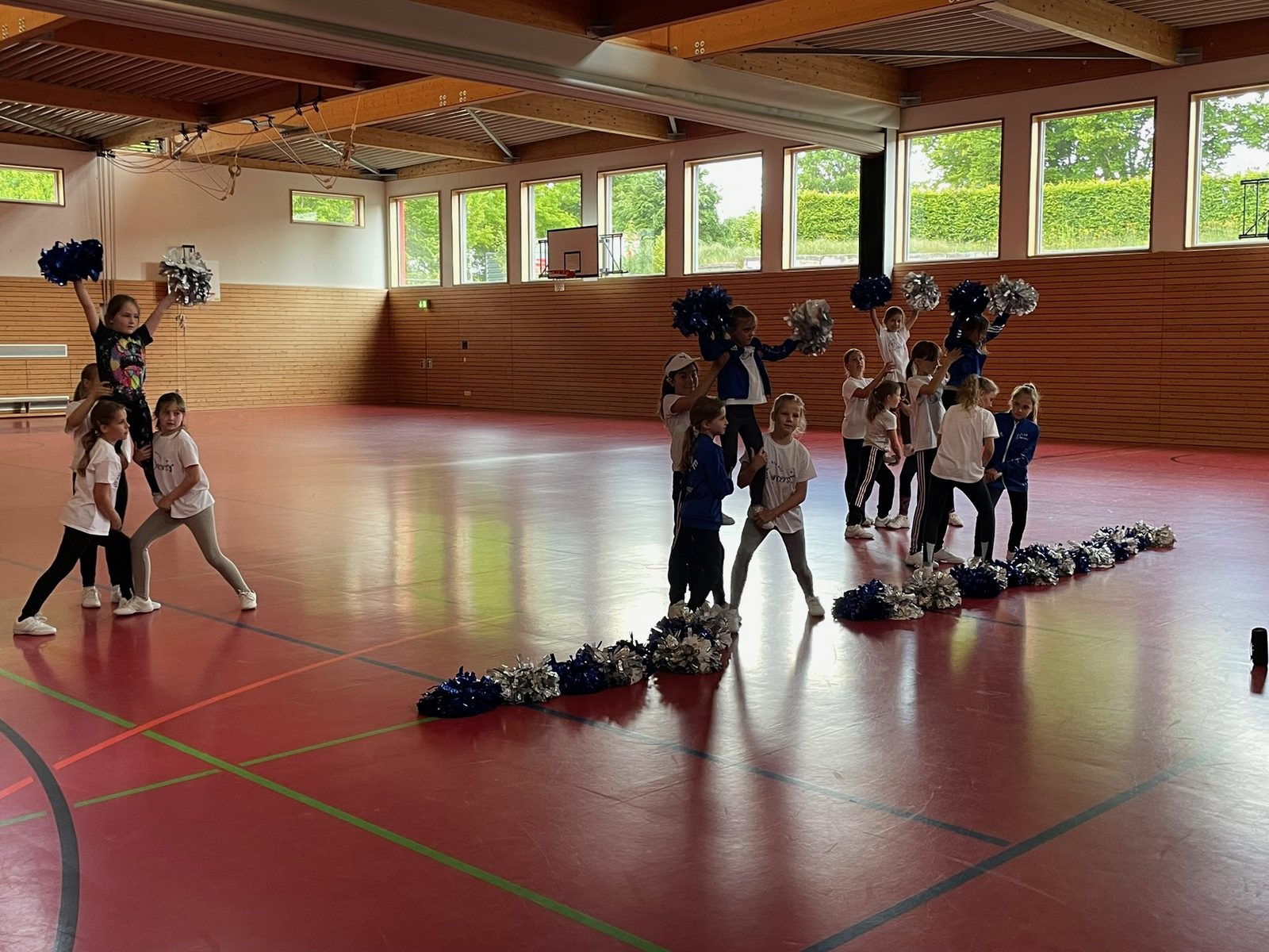 Der Dancers-Nachwuchs übt in der Sporthalle eine Choreografie mit Hebefiguren und blau-silbernen Pom-Poms