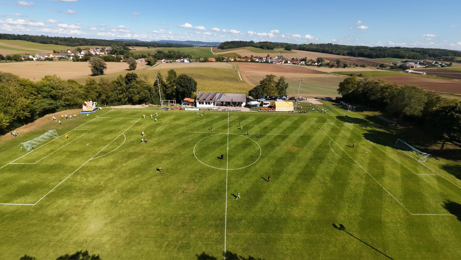 Luftaufnahme des Sportgeländes in Niederhofen mit Sportheim, Fußballplatz und umliegender Rieslandschaft