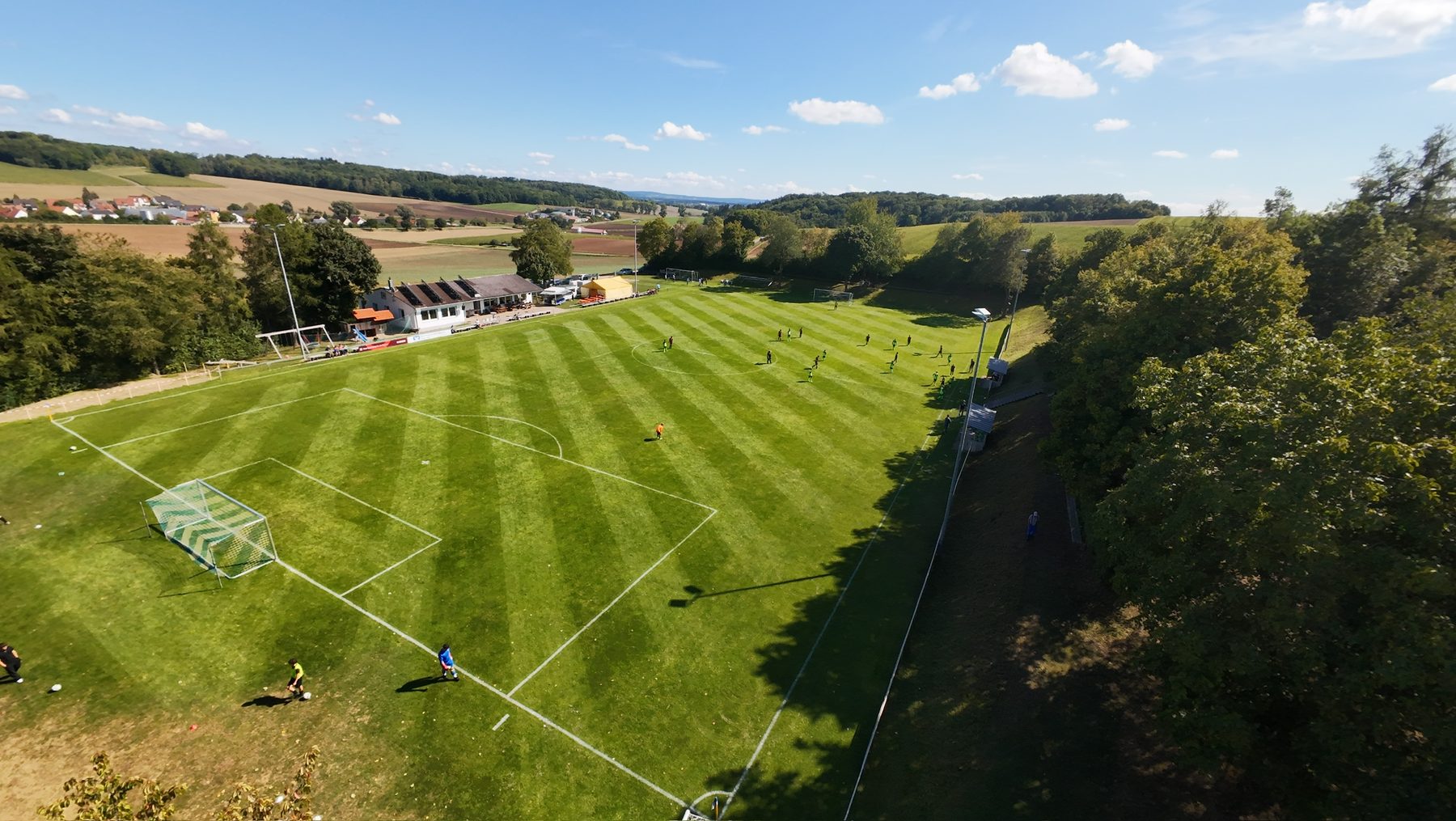 Luftaufnahme des Sportheims Niederhofen mit Solaranlage auf dem Dach und dem angrenzenden Fußballplatz