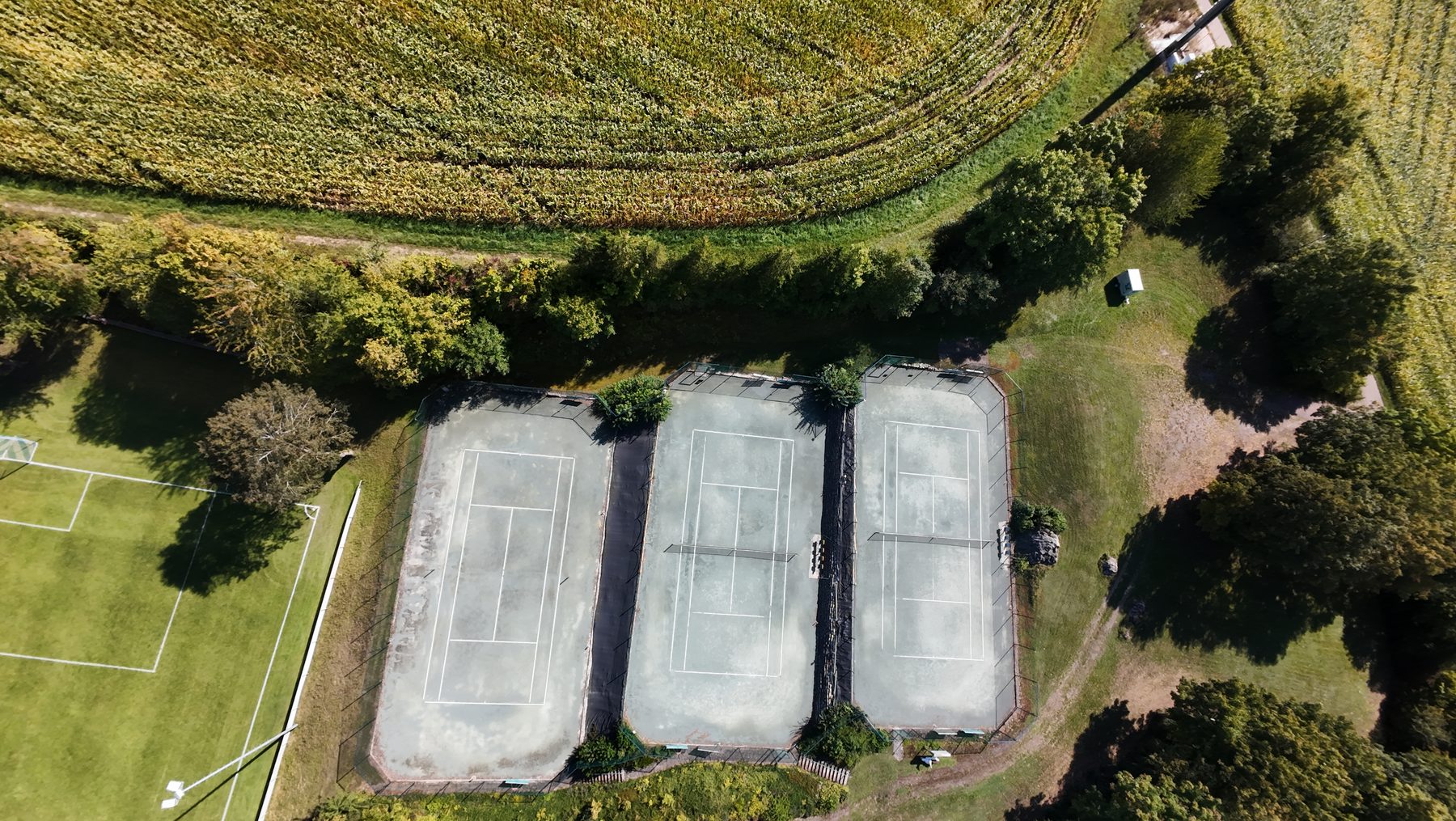 Luftaufnahme von direkt oben auf die drei Tennisplätze am Sportgelände Niederhofen
